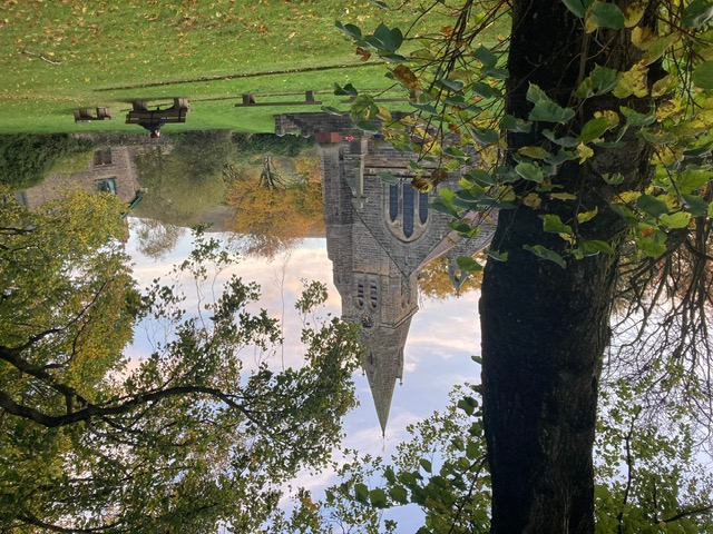 Historic stone church surrounded by lush greenery and autumn foliage, offering a serene outdoor setting