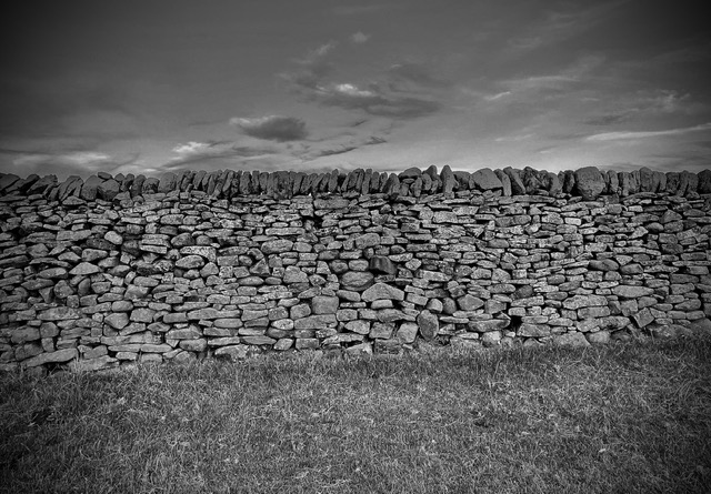 Dry stone wall with rugged texture and grassy foreground, showcasing traditional craftsmanship in a serene landscape