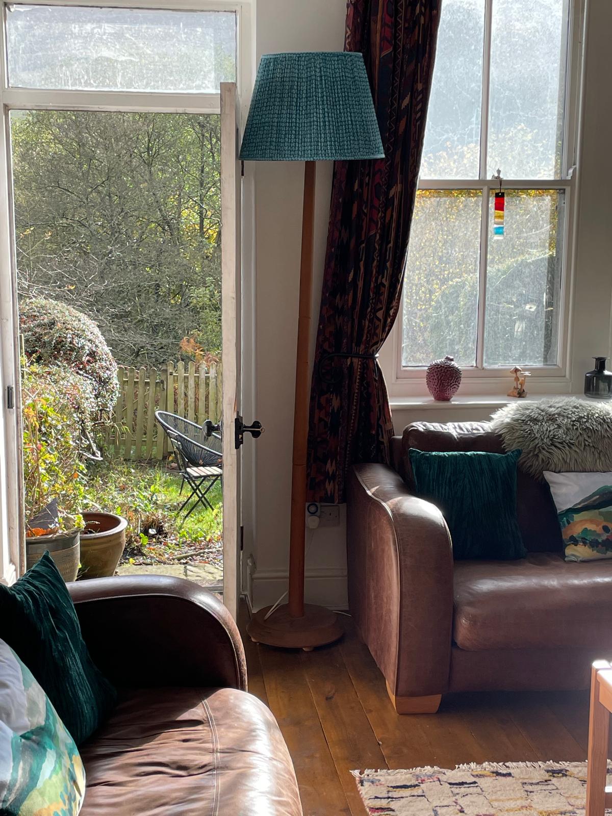 Cozy luxury cottage living room with leather sofas, a stylish floor lamp, and garden views through large windows