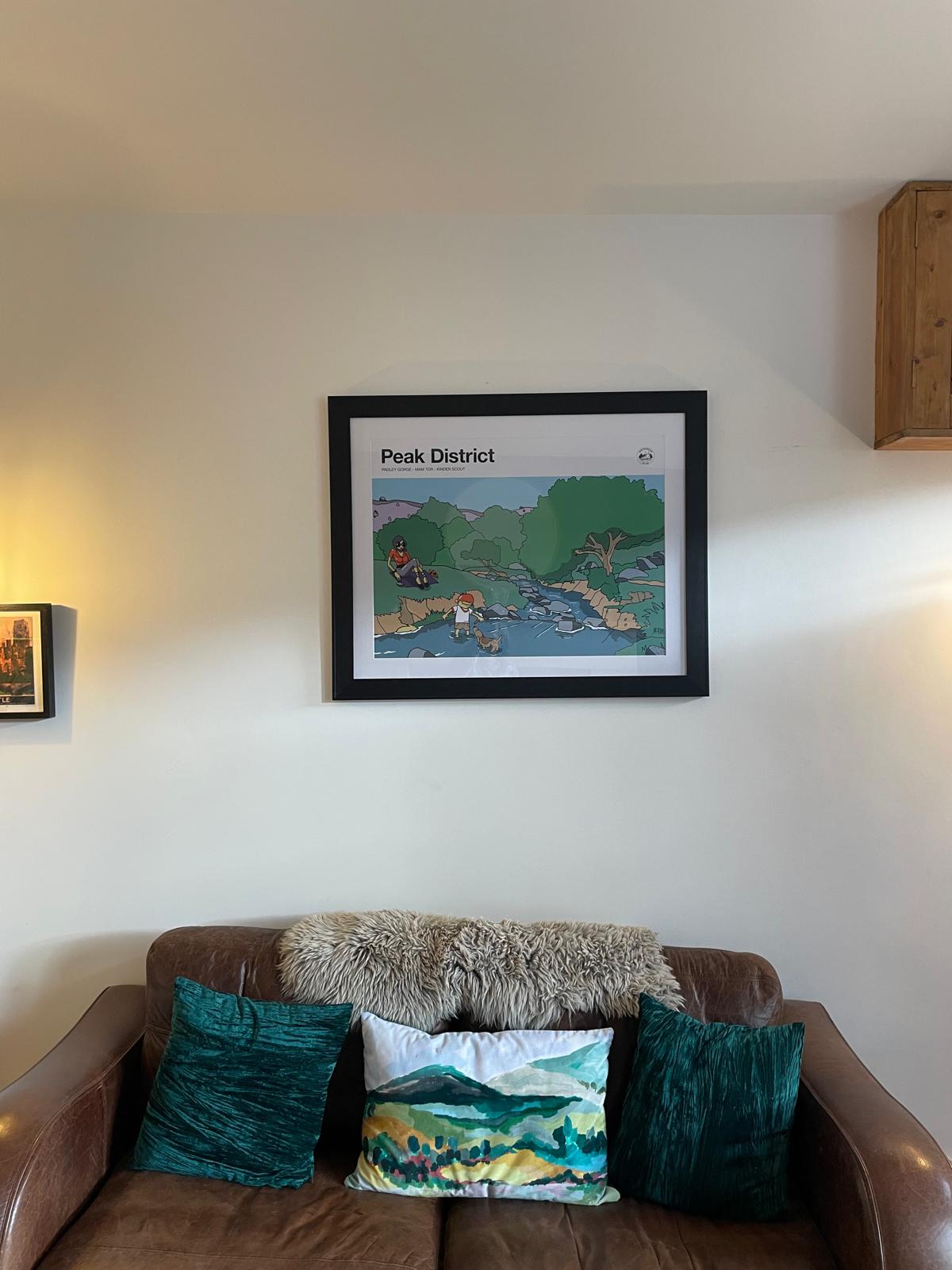 Cozy living room with a leather sofa, decorative cushions, and framed art, featuring a warm and inviting atmosphere