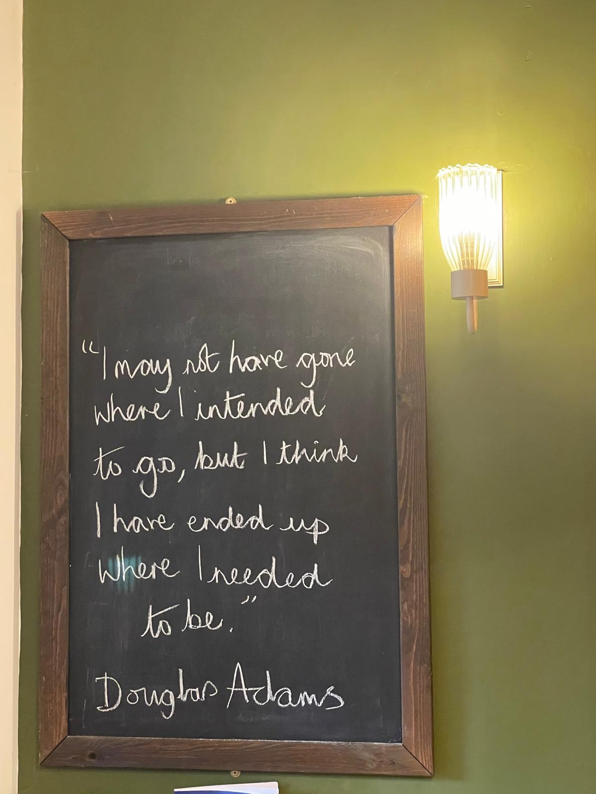 Charming cottage interior with a framed quote on a green wall, featuring stylish lighting and cozy decor elements