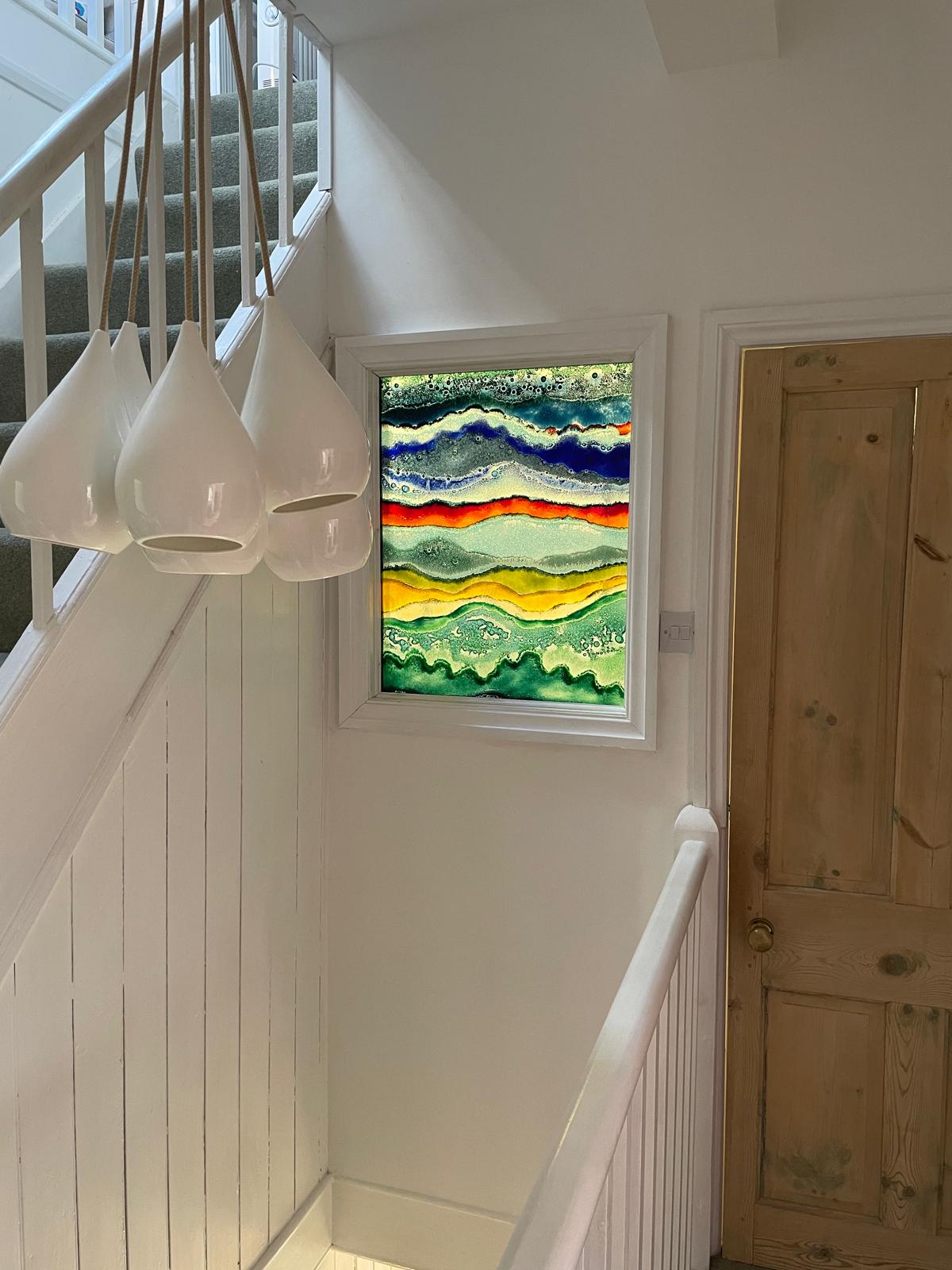 Bright hallway featuring modern pendant lights and a colorful abstract artwork, enhancing the luxury cottage ambiance