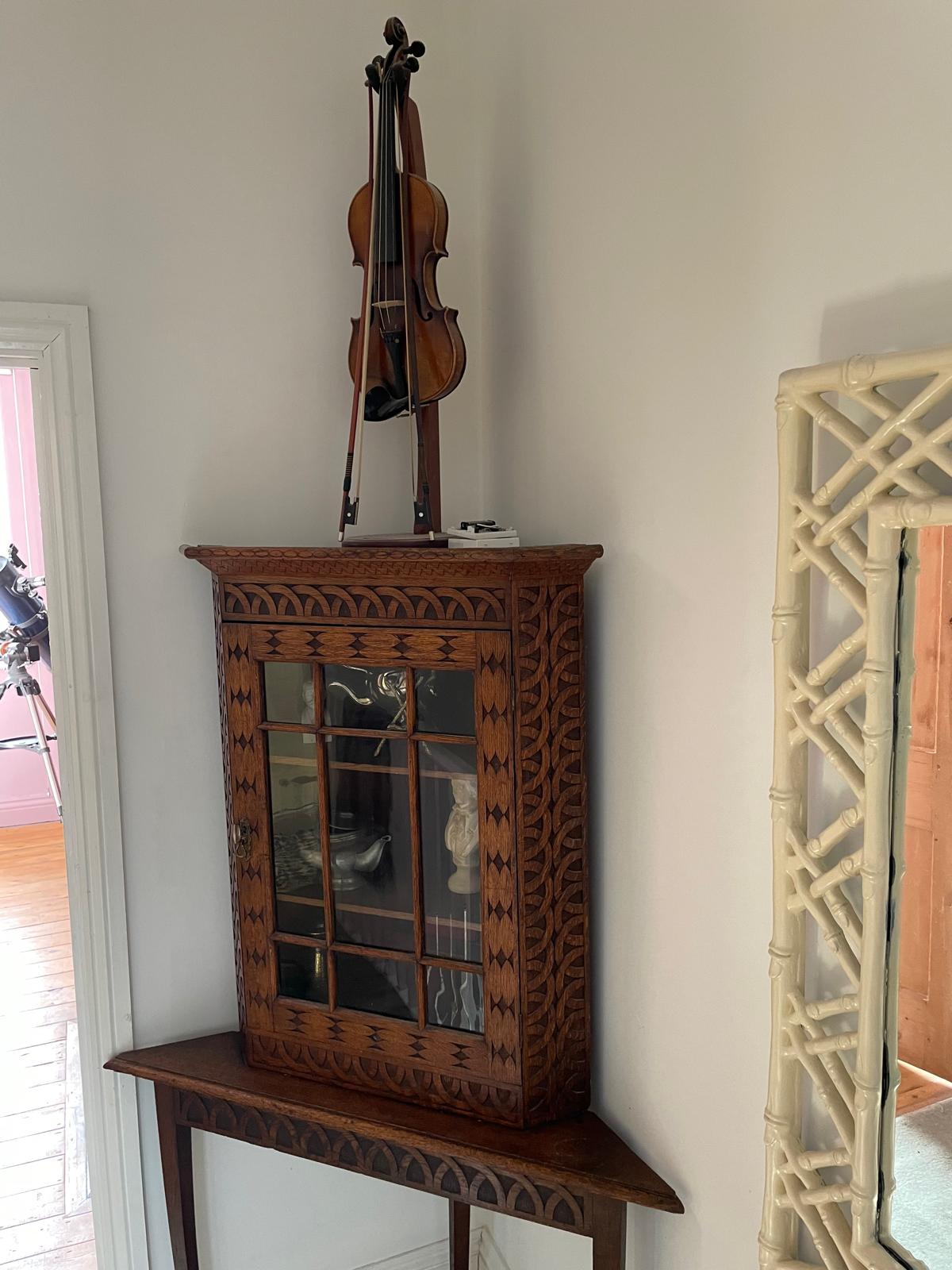 Elegant wooden display cabinet with intricate carvings, featuring a violin atop, enhancing the luxury cottage ambiance