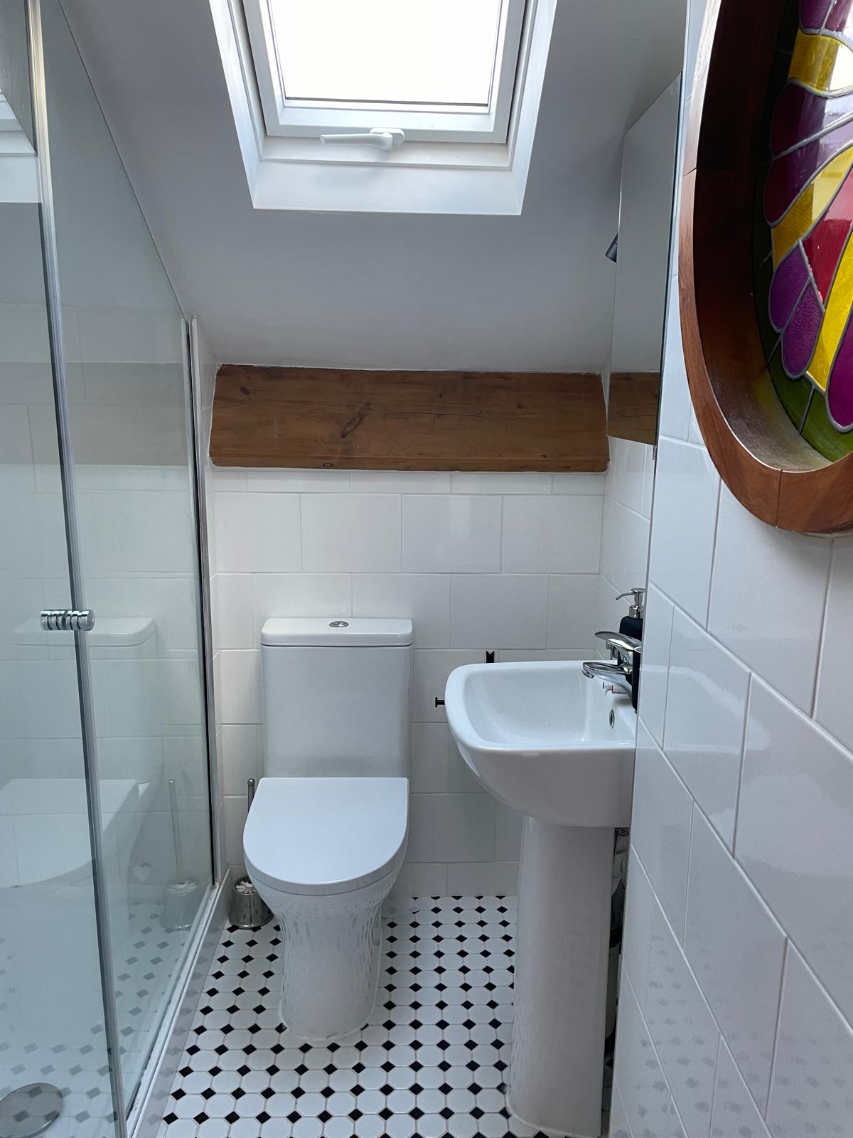 Modern bathroom featuring a walk-in shower, stylish sink, and unique stained glass window accents