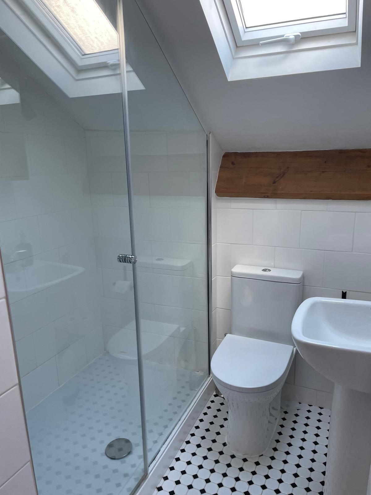 Modern bathroom with glass shower, white tiles, and wooden accents in a luxury cottage setting