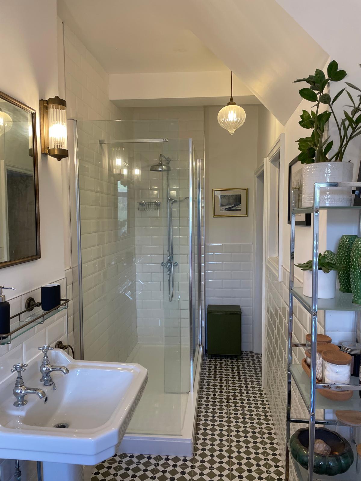Luxury bathroom featuring a walk-in shower, vintage sink, stylish tiles, and elegant lighting