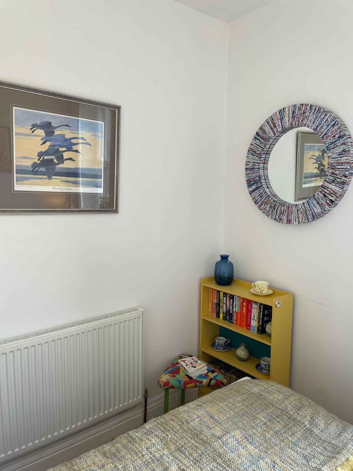 Cozy luxury bedroom with colorful decor, bookshelf, mirror, and warm lighting for a relaxing stay