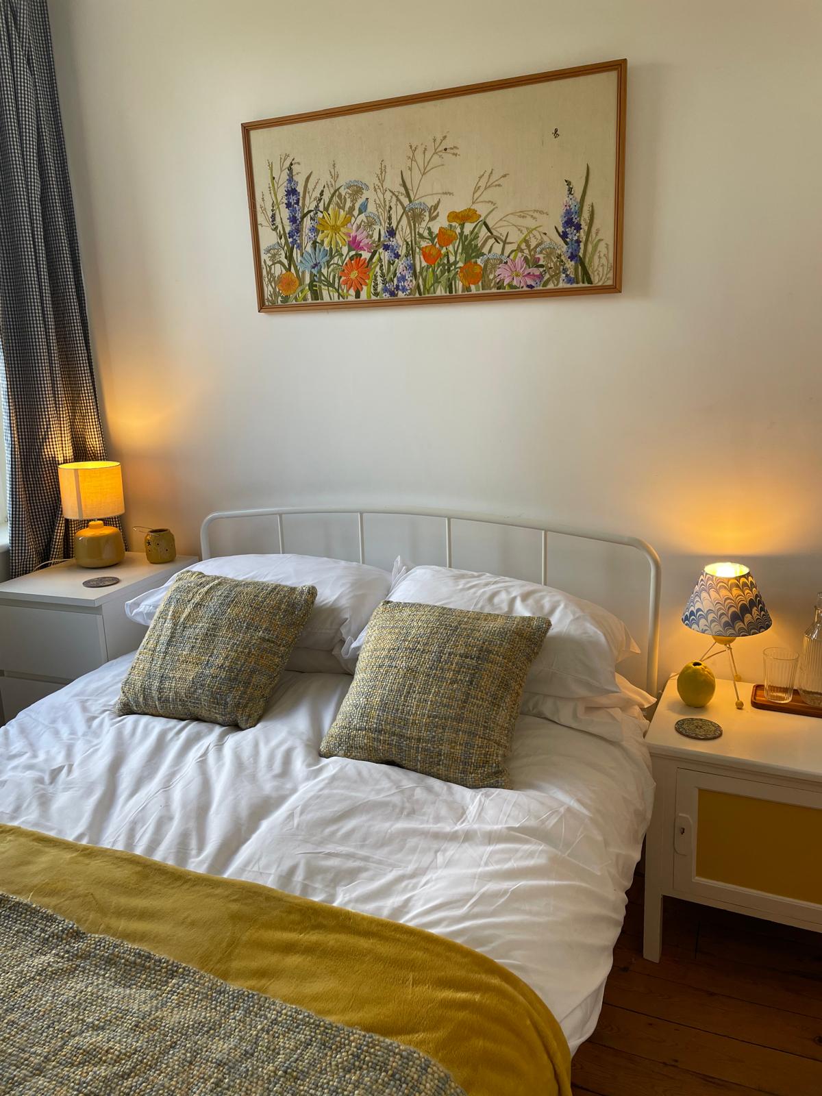 Cozy luxury bedroom with a double bed, decorative pillows, bedside lamps, and floral artwork