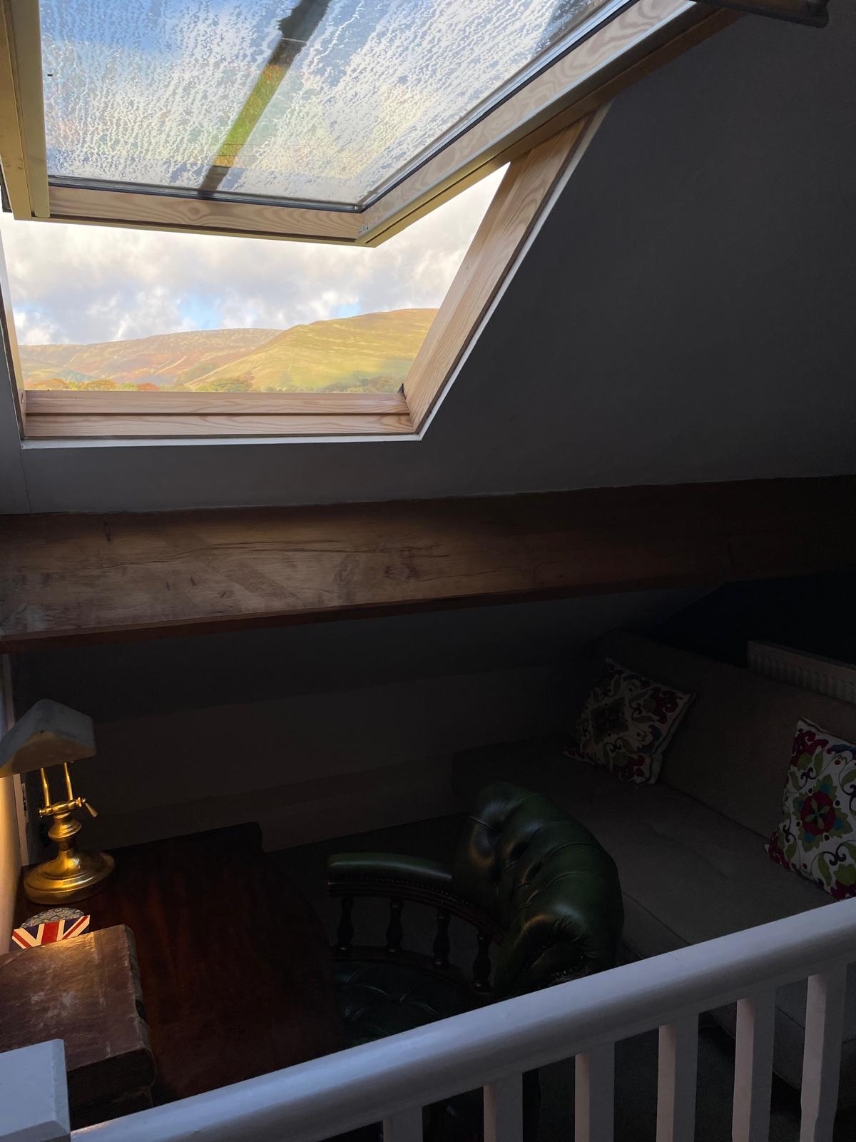 Cozy luxury cottage living area with a skylight, vintage furniture, and scenic mountain views