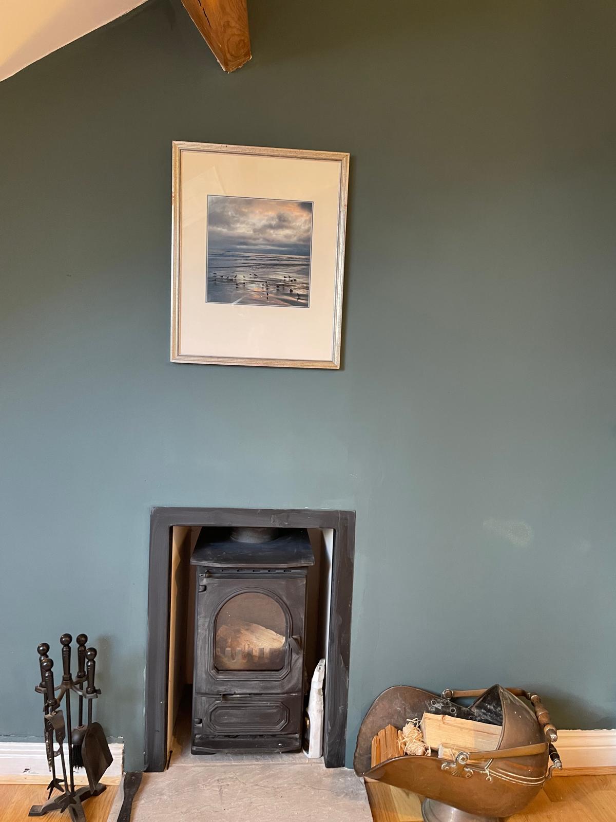 Cozy luxury cottage interior featuring a wood-burning stove, framed artwork, and rustic decor elements