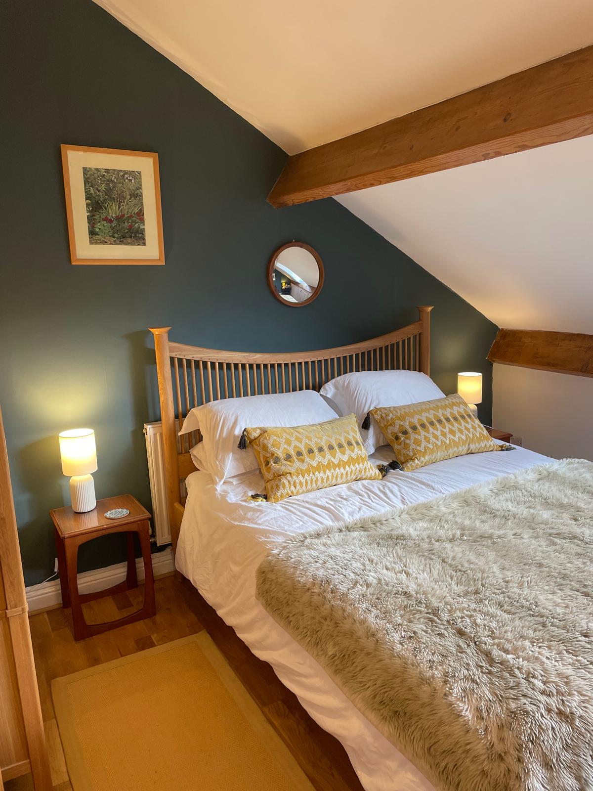 Cozy luxury bedroom with wooden beams, double bed, decorative pillows, and warm lighting