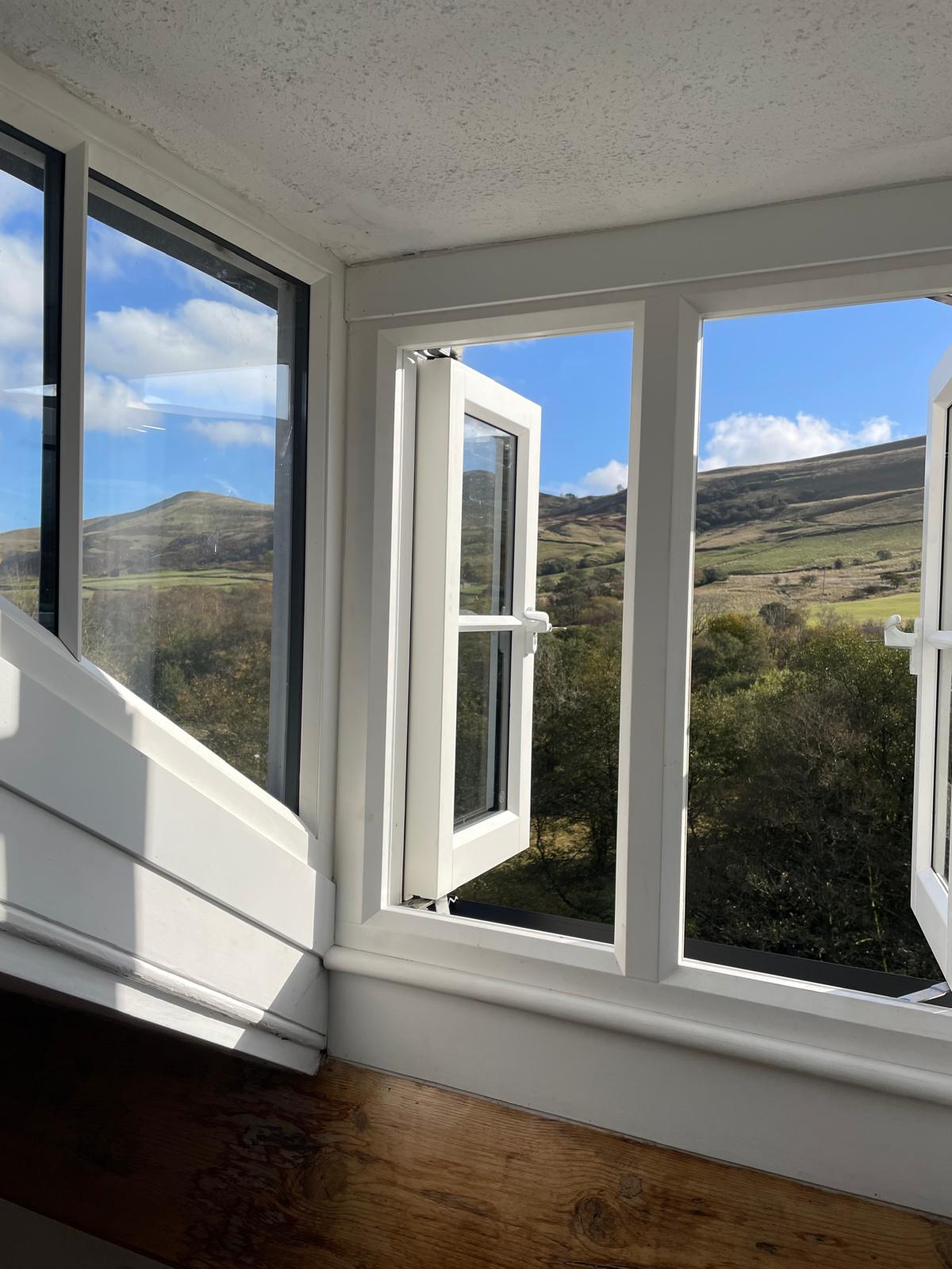 Luxury cottage bedroom with large windows offering stunning mountain views and natural light