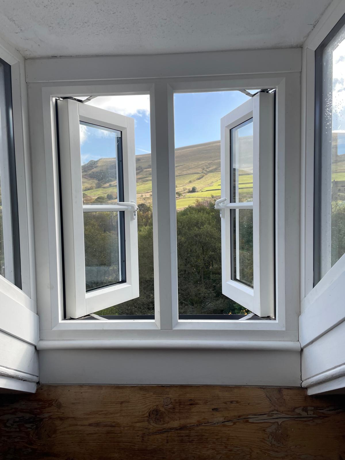 Luxury cottage window with scenic mountain views, featuring white frames and natural light illuminating the interior