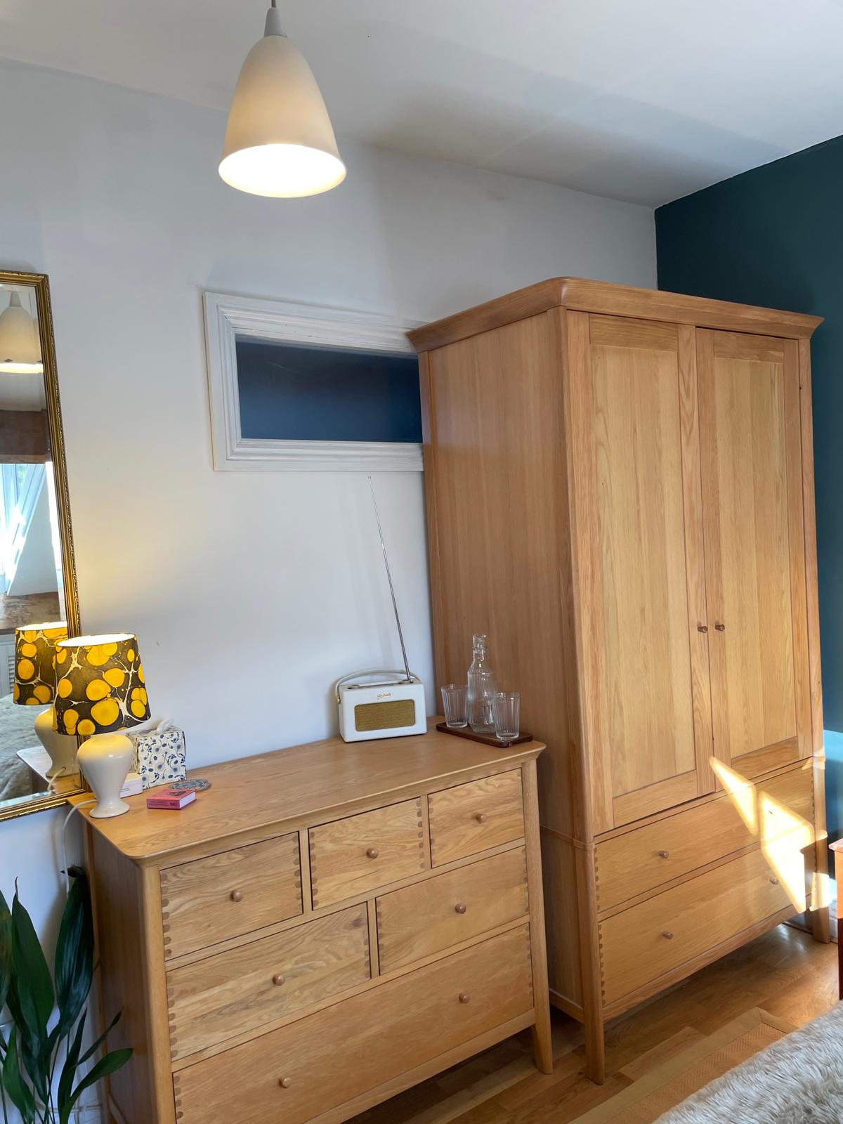 Cozy luxury cottage bedroom featuring wooden furniture, stylish lamp, and natural light. Perfect for a relaxing getaway
