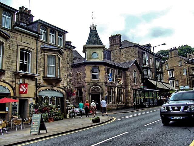 Charming street view of Dunelm Cottage with stone architecture, shops, and outdoor seating in a vibrant village setting